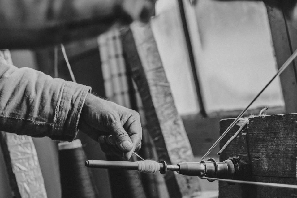 A craftsperson hand-spinning cotton yarn at the AZOR workshop