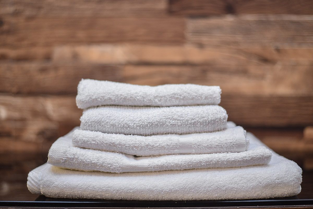 A stack of premium AZOR cotton towels in soft, warm light